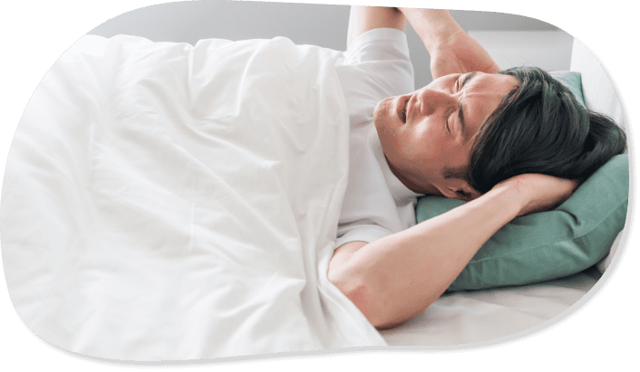 男性がベッドに横になって頭を抱えている様子